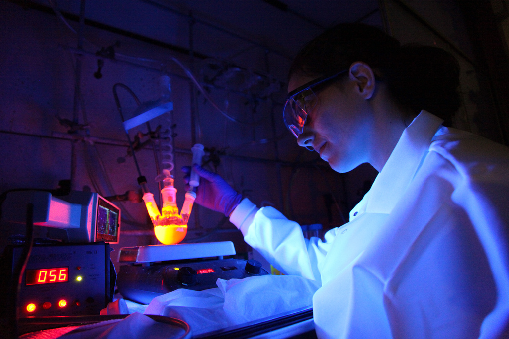 A student in a dark room uses instruments which appear to be glowing.