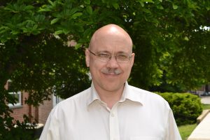 A headshot photo of Gregory Eyink outdoors in front of a tree on campus.