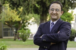 A headshot of Gonzalo Pita wearing a dark blue color suit standing in a garden