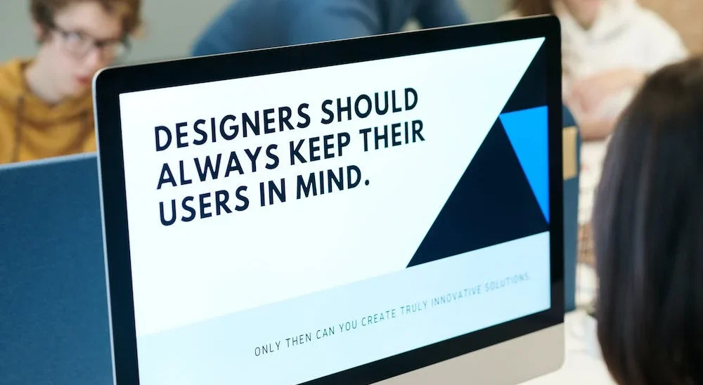 A monitor displays the text "Designers should always keep their users in mind. Only then can you create truly innovative solutions."