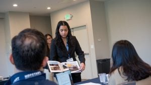Remi team members displaying a book, part of their memory sharing app, to judges during their pitch at HopStart 2026.