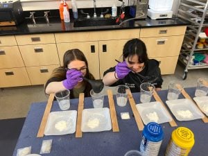 Team members measuring silicon and other liquids in measuring cups in the lab.