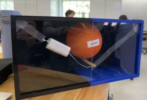 A product display including a bladder modeled by the orange balloon, the urethra modeled by the opaque tube, the prototype sling made of white surgical mesh, and the white 3D-printed linear adjustment region.