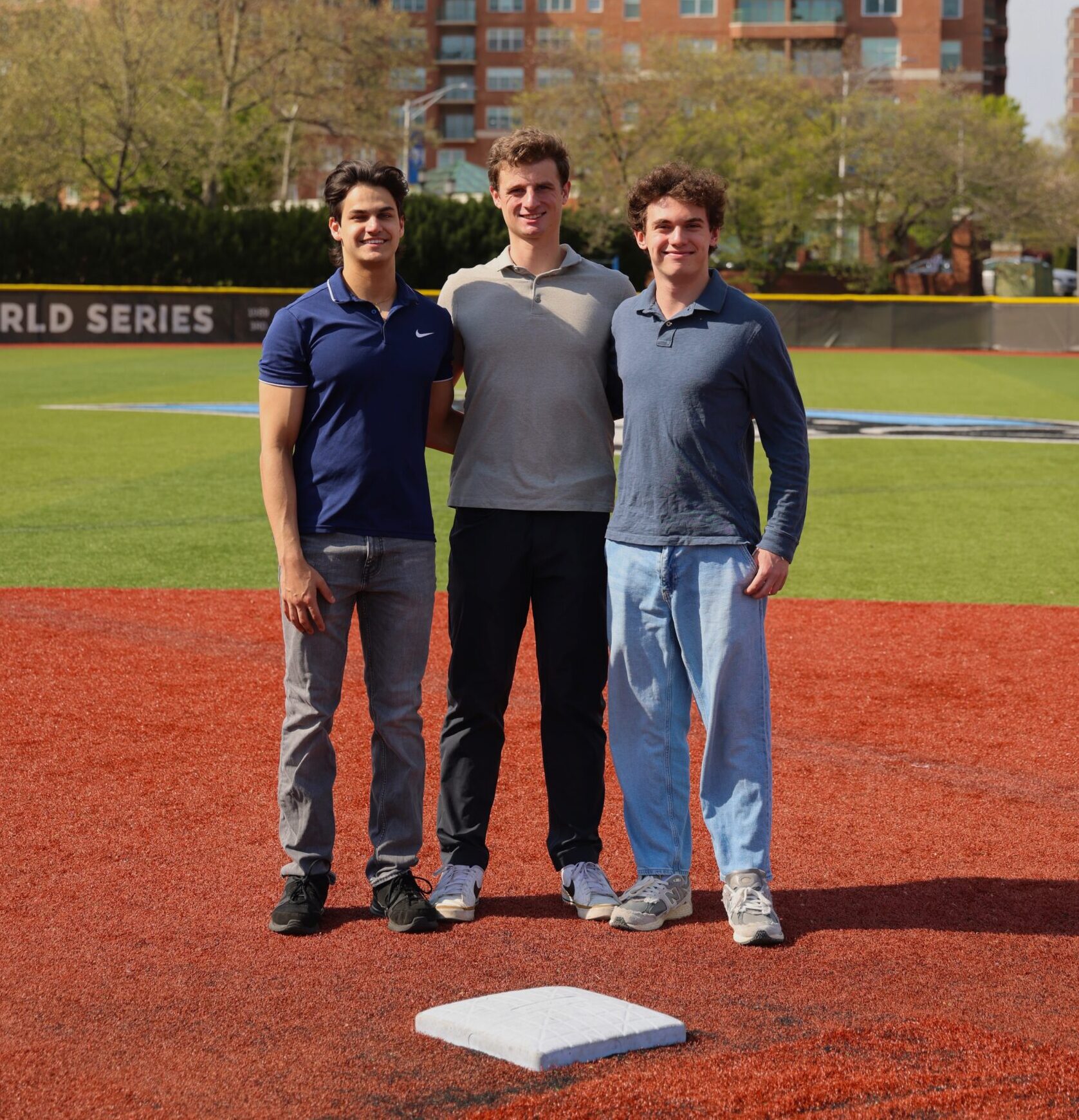 three young men posing in a baseball field