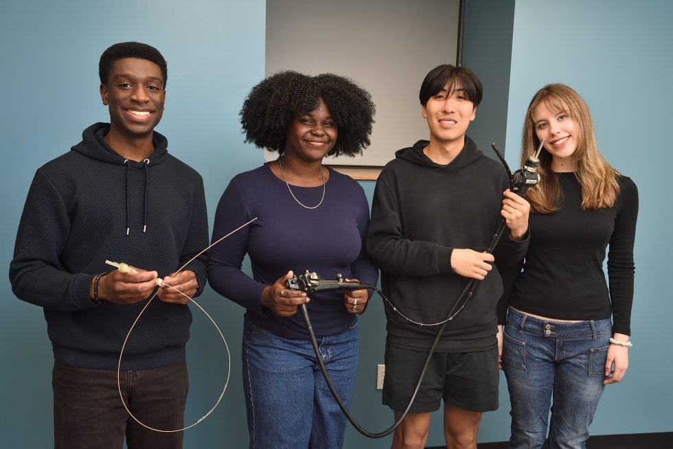 4 students standing next to each other holding the prototype that they have made