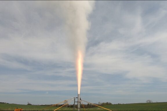 Rocket engine firing upwards on a vertical static-test stand. Mach diamonds visible in shot.