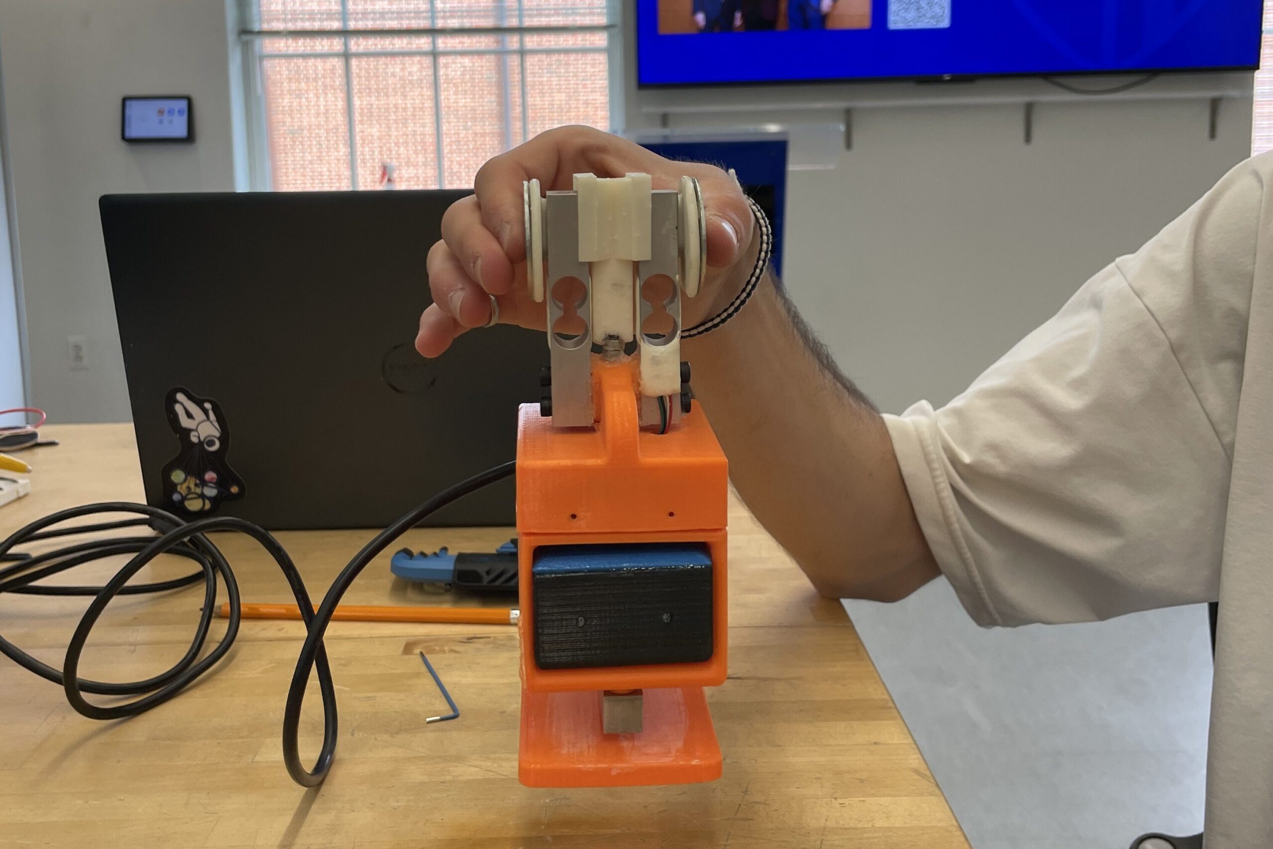 3D-printed SenseHand device being lifted with a pinch grip while measuring grip and load forces.