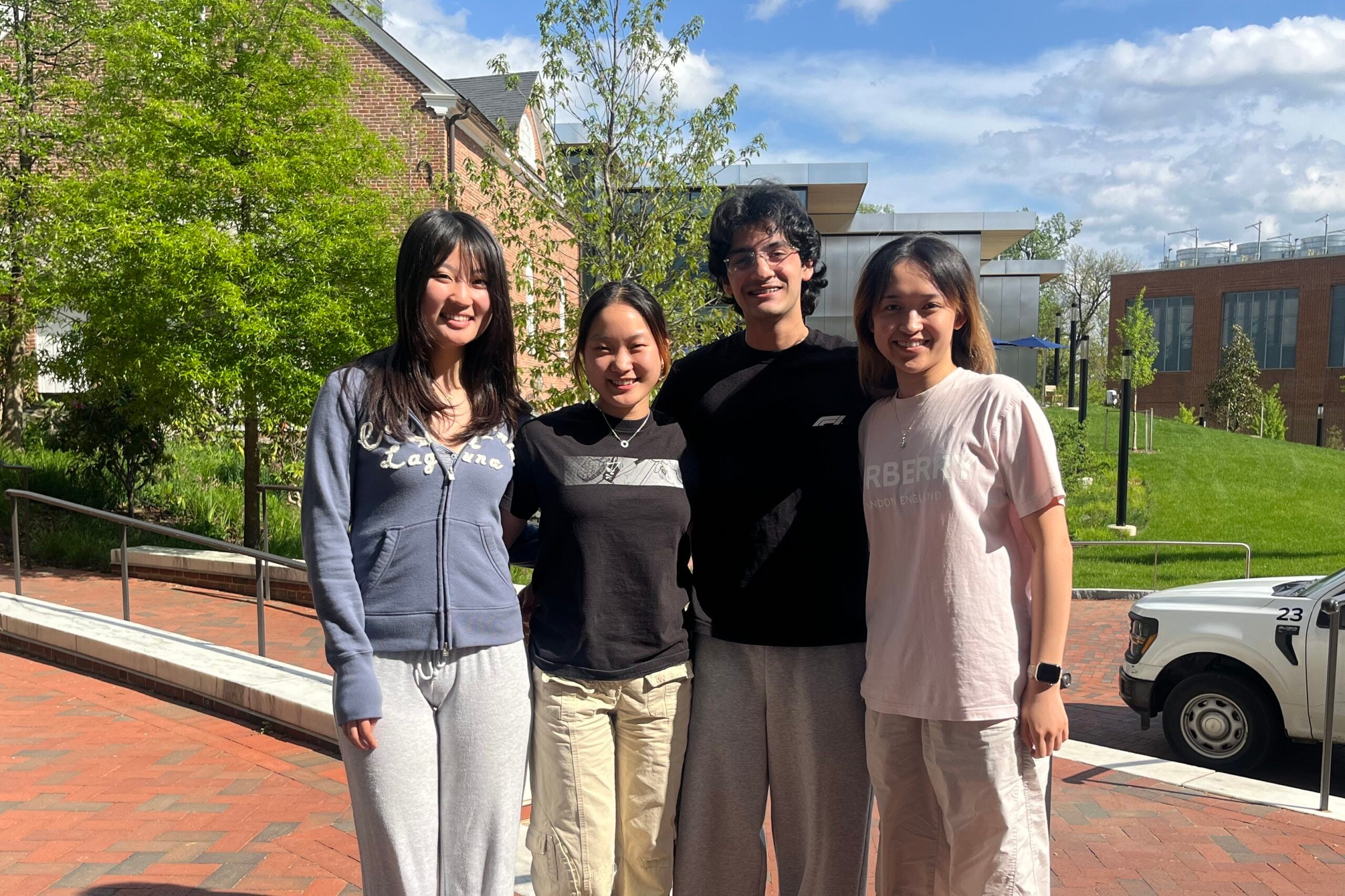 Four students smiling, standing outside