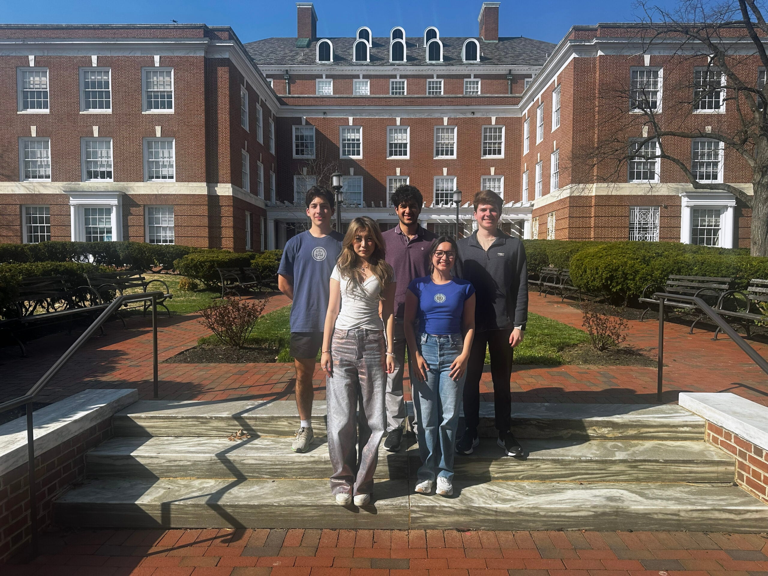 Five students standing on steps