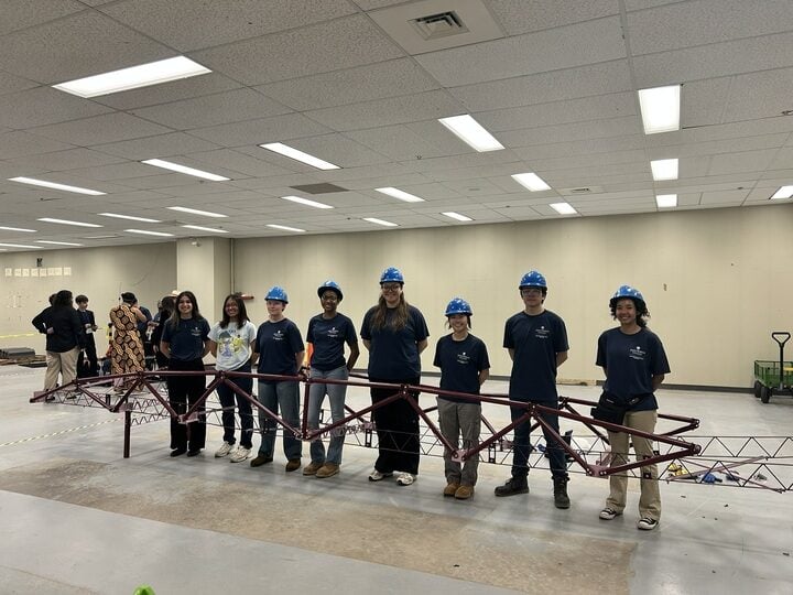 Students are standing in front of a 25 ft long steel bridge built for competition