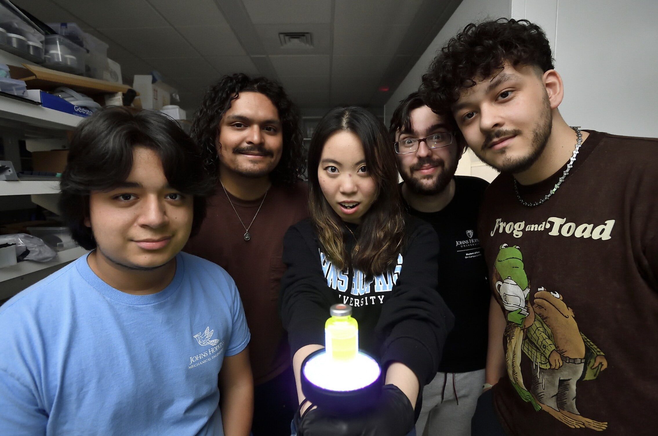 Five students surround a brightly glowing container which hold a small amount of quantum dots.
