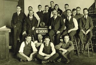 Flanking a sign being ignored by one pipe smoker, professors Carl Clapp Thomas and Alexander Graham Christie (mustache) gather with the Class of 1917 Mechanical Engineering students.