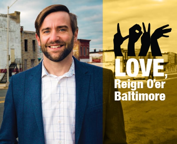 Scott Burkholder '02 stands in front of a LOVE mural