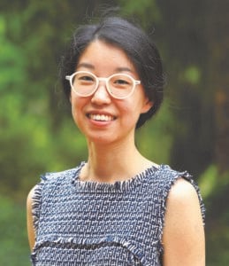 Photo of Jean Fan with a blue and white twill top and green background.
