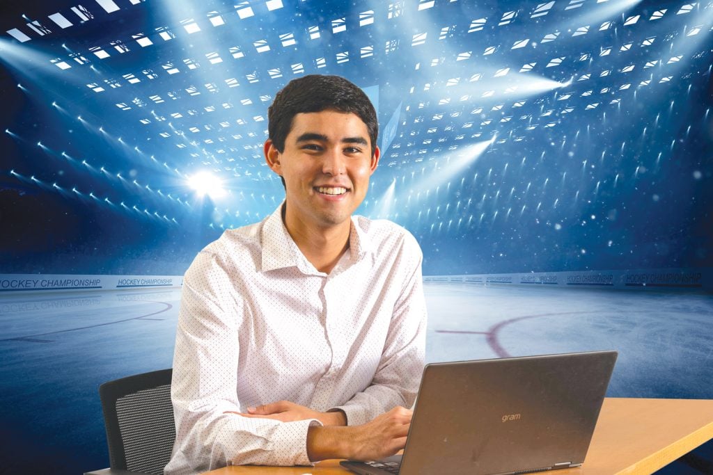 Tad using a computer in an empty ice hockey rink.