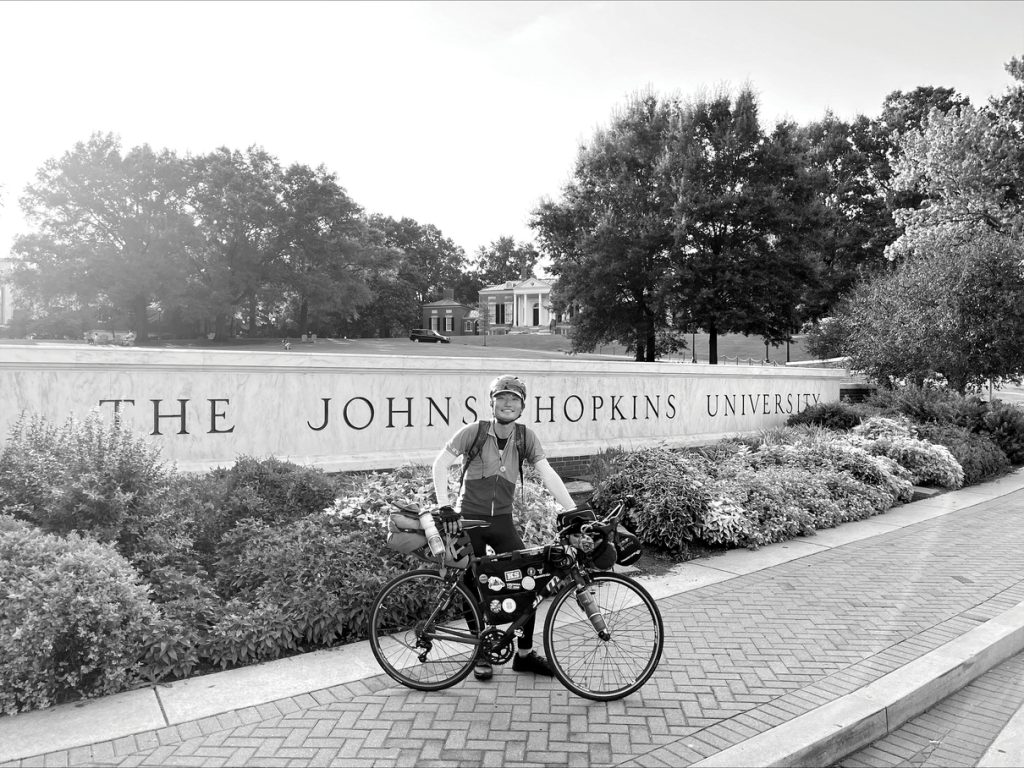 Chun-Chiao Yang pictured in front of a wall that reads 'The Johns Hopkins University'.