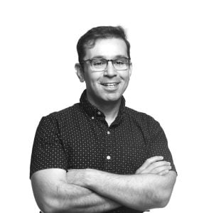 grayscale photo of Daniel Khashabi standing with his arms crossed in front of his chest