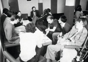 black-and-white image of a room full of students supervised by Stephen Hawking