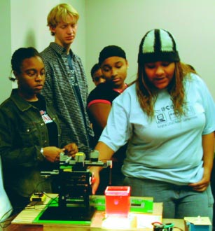 In a surgical simulation, high school students test their LEGO robot by targeting a “tumor” (a grape plays the part, embedded in Jell-O).