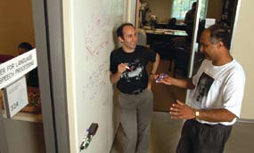 Jason Eisner (left) and Sanjeev Khudanpur toss ideas around a whiteboard in the hallway outside the offices of the Center for Language and Speech Processing.
