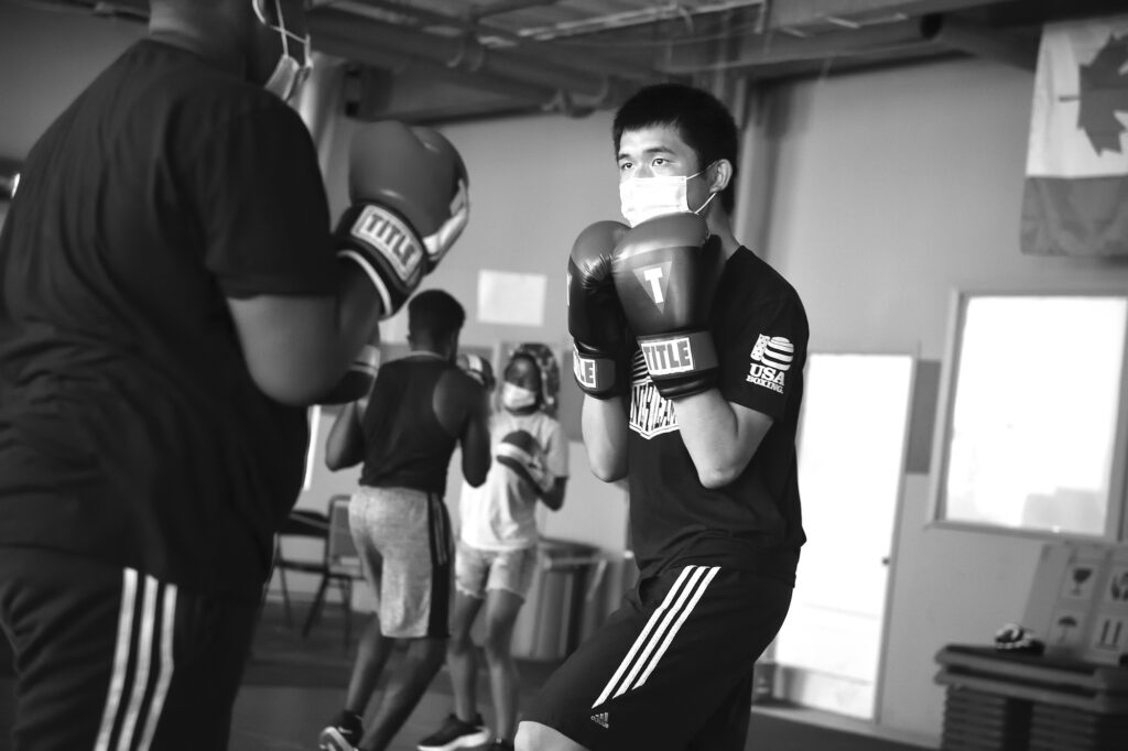 Two men wearing boxing gloves stand across from each other as part of a boxing lesson