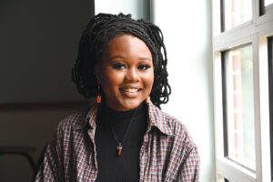 Photograph of Michelle Mokaya, smiling, seated by a window