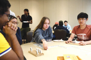 Photograph of Cristina De Jong playing dominoes with a Cuban flag embossed on the back