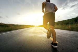 photograph of a man running down a road toward a setting sun