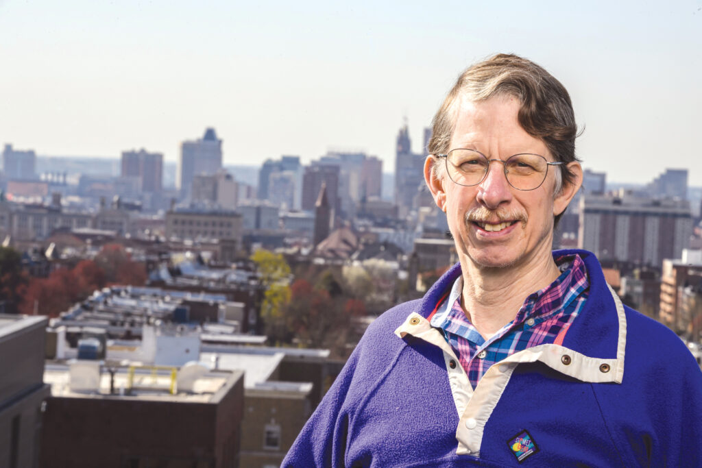 Professor Ben Hobbs pictured smiling in front of a city skyline.