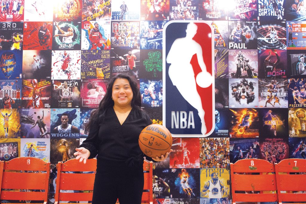 Paige Senal holding a basketball while standing in front of an NBA backdrop