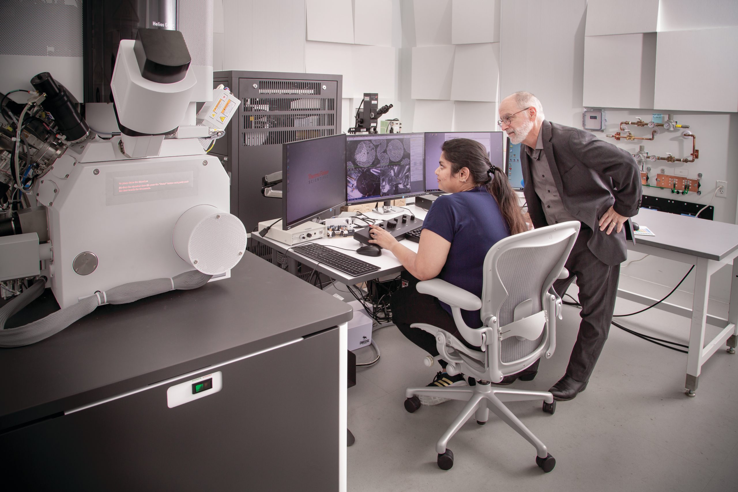 Image of two people looking at images made on a focused ion beam-scanning electron microscope