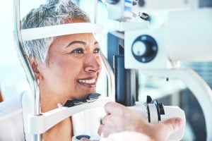 A photo of a woman smiling, receiving an eye exam