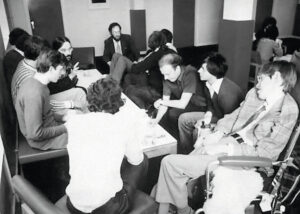 black-and-white image of a room full of students supervised by Stephen Hawking