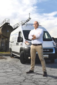 image of Peter DeCarlo standing next to his MOM+POP mobile laboratory van