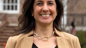 A headshot of Mitra Taheri wearing a brown blazer standing outdoors of the campus.