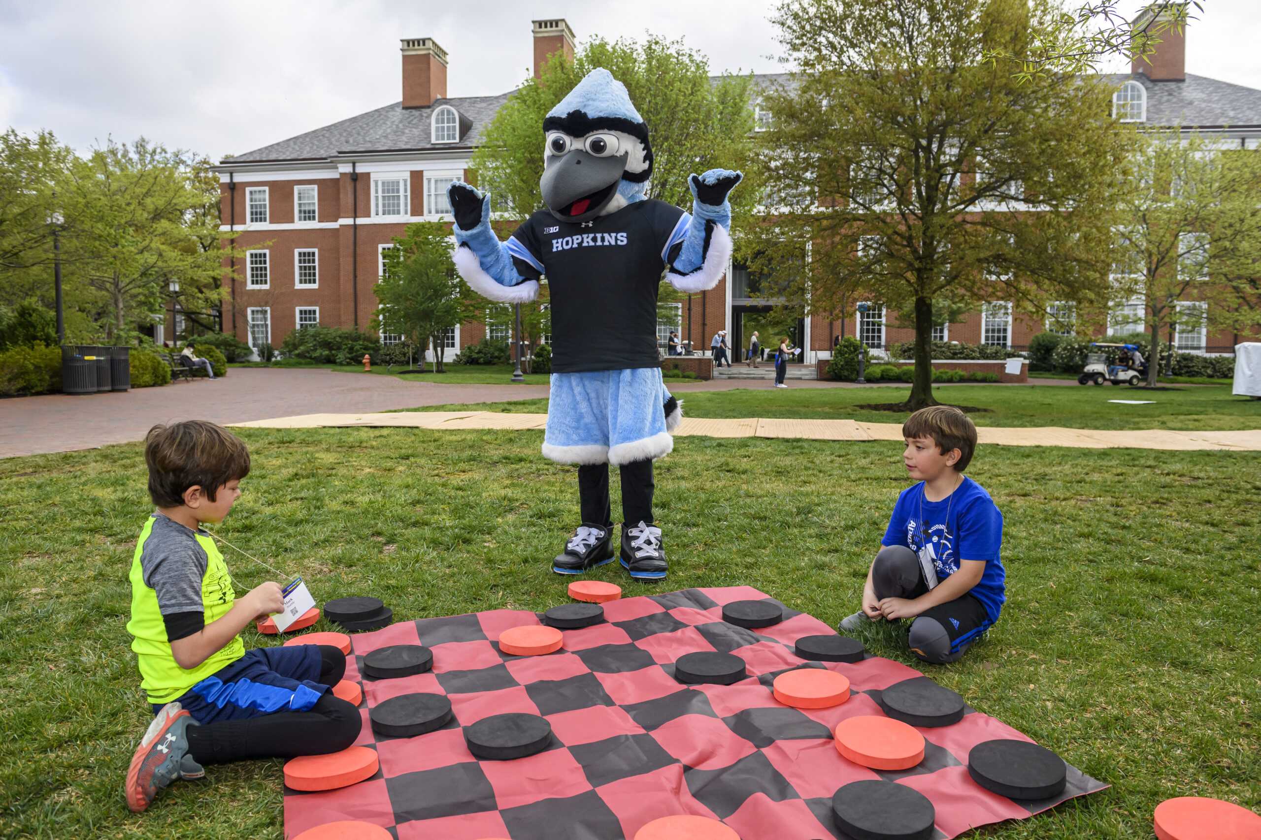 Blue Jay mascot interacting with children playing giant checkers lawn game