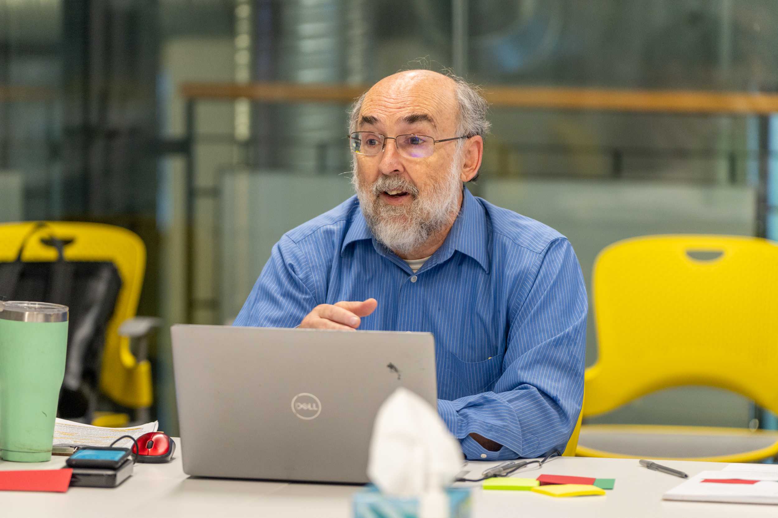 Facilitator Dr. Chuck Montague at the Advanced Grant Writing: Specific Aims Workshop sitting at a table in front of a computer and speaking.