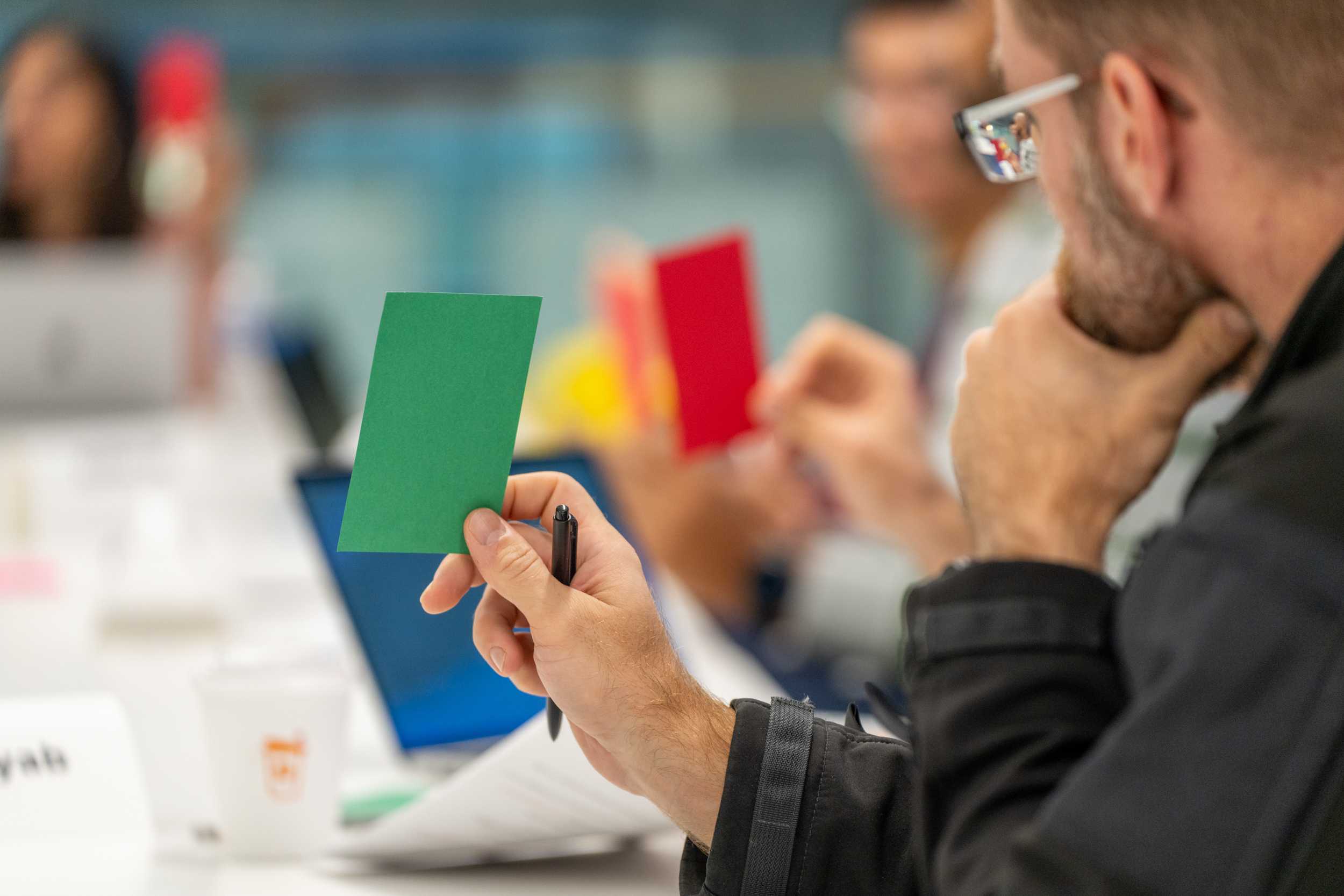 Participants in the Advanced Grant Writing workshop holding up red and green colored paper during an activity.