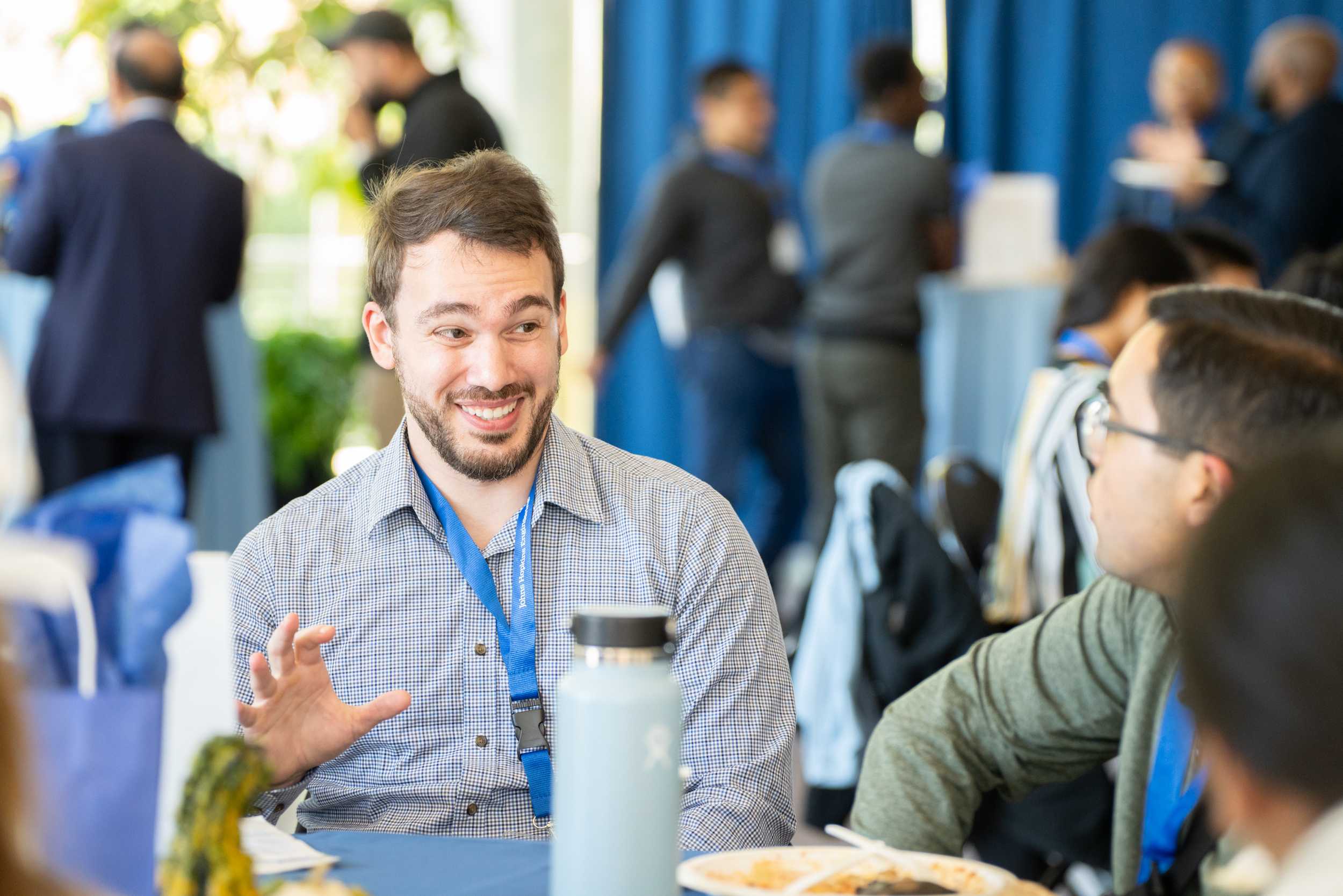 Connect to Campus attendees sitting at a table and talking with plates of food in front of them.