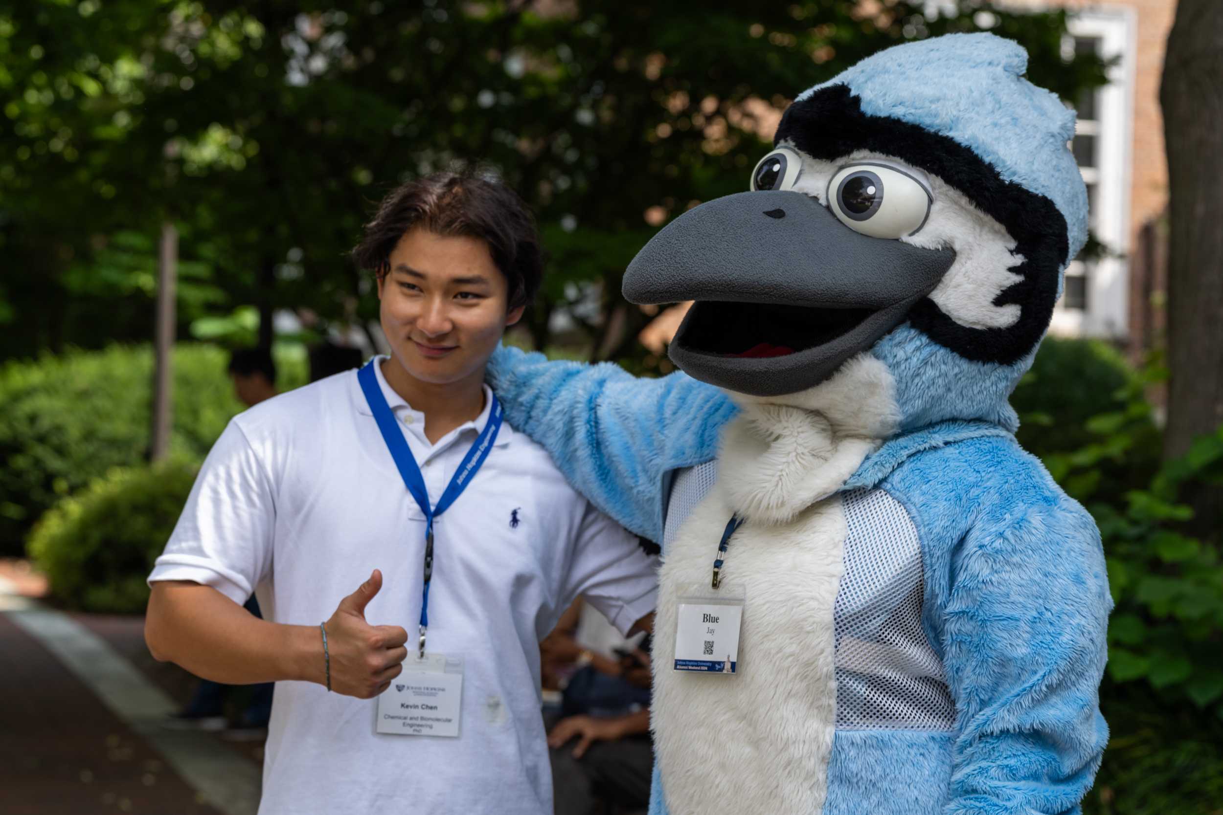Student posing Blue Jay mascot and giving a thumbs up.