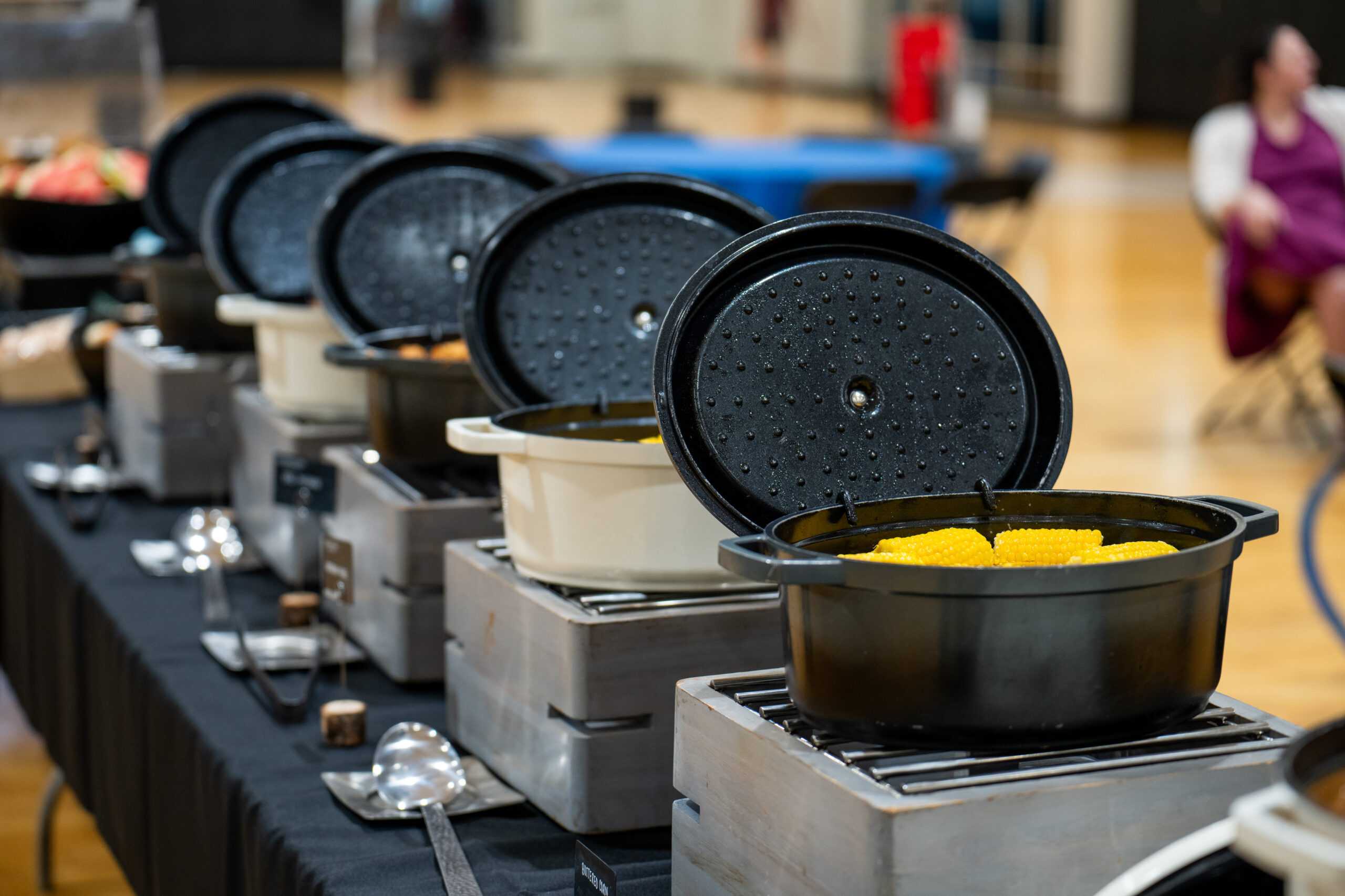 Catering table with several crock pots containing food like corn on the cob