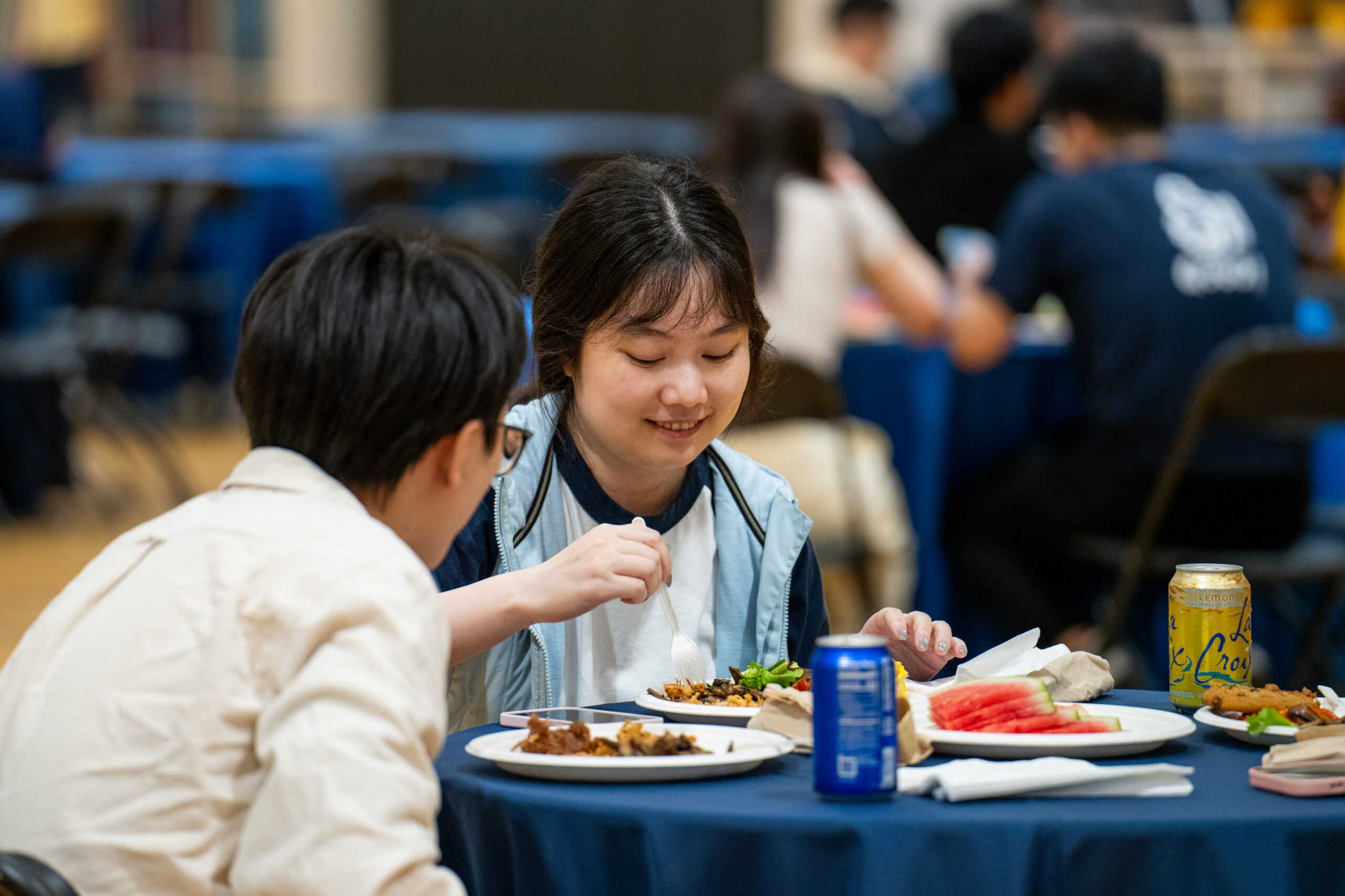 Attendees sitting at a table and eating during the 2024 Masters graduate BBQ.