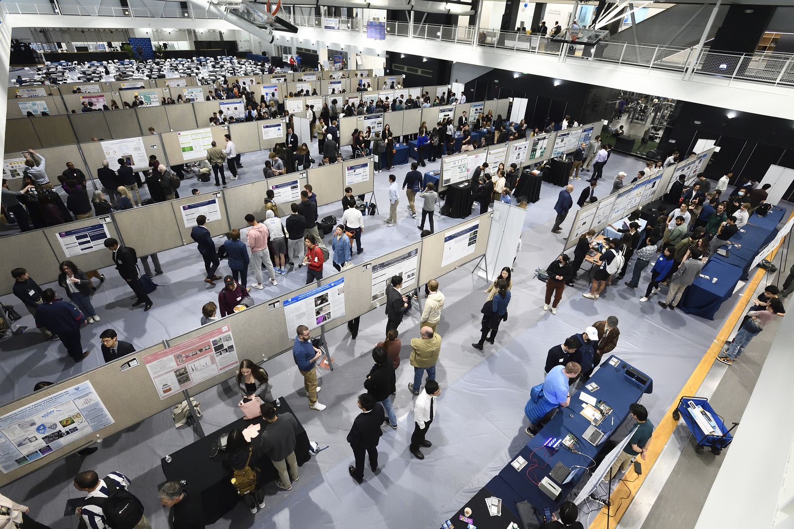 People walking through rows full of displayed design posters.