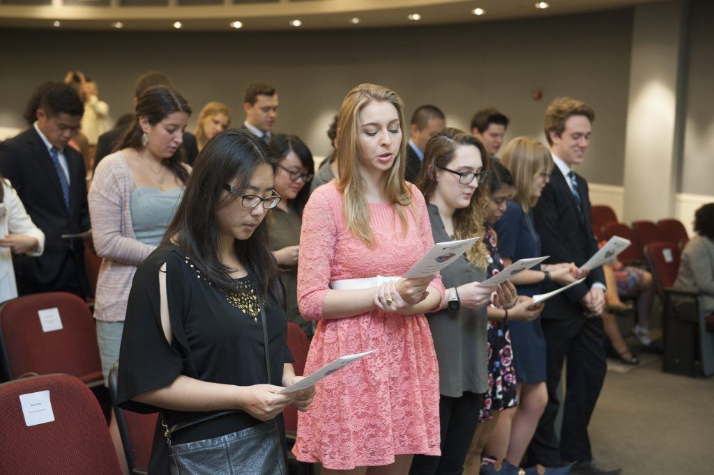 Students reading a pledge of the backs of event programs.