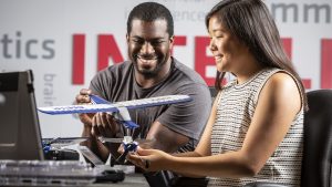 A man and woman holding airplane models while sitting on chairs.