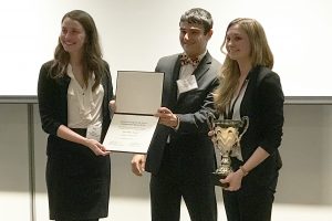 Jourdan Ewoldt receiving a trophy along with two people.