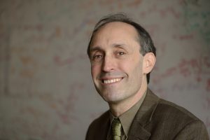A headshot of Jason Eisner wearing a brown blazer.