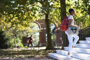 The side view of a woman climbing up the stairs, outdoors of the campus.