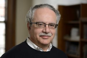 A headshot of Yannis Kevrekidis wearing a black sweater over a white shirt.