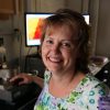 A headshot of Patricia McGuiggan with a monitor in the background